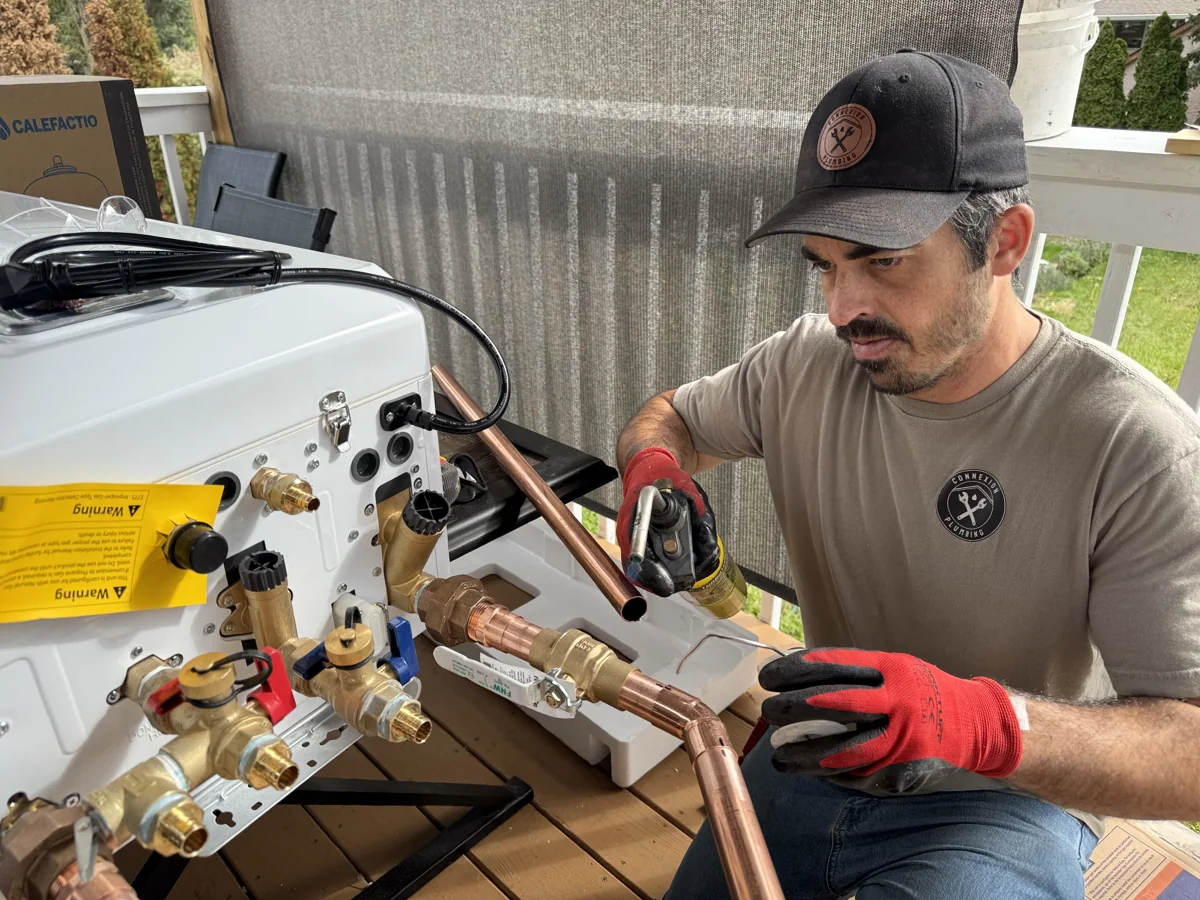 Marc preparing a combi boiler for installation, working on its copper pipe connections.