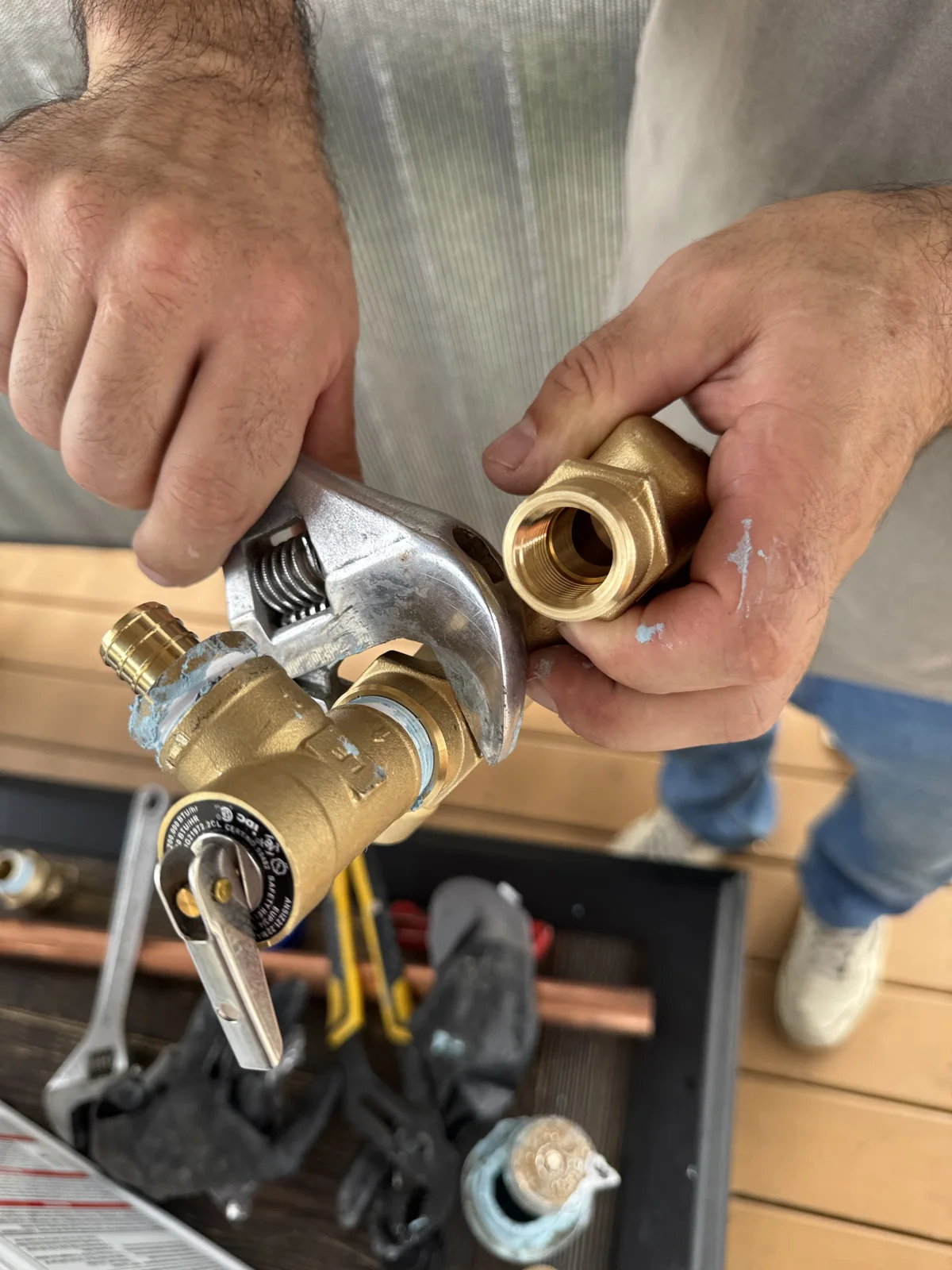 Marc using a wrench to install a brass relief valve on a plumbing assembly.