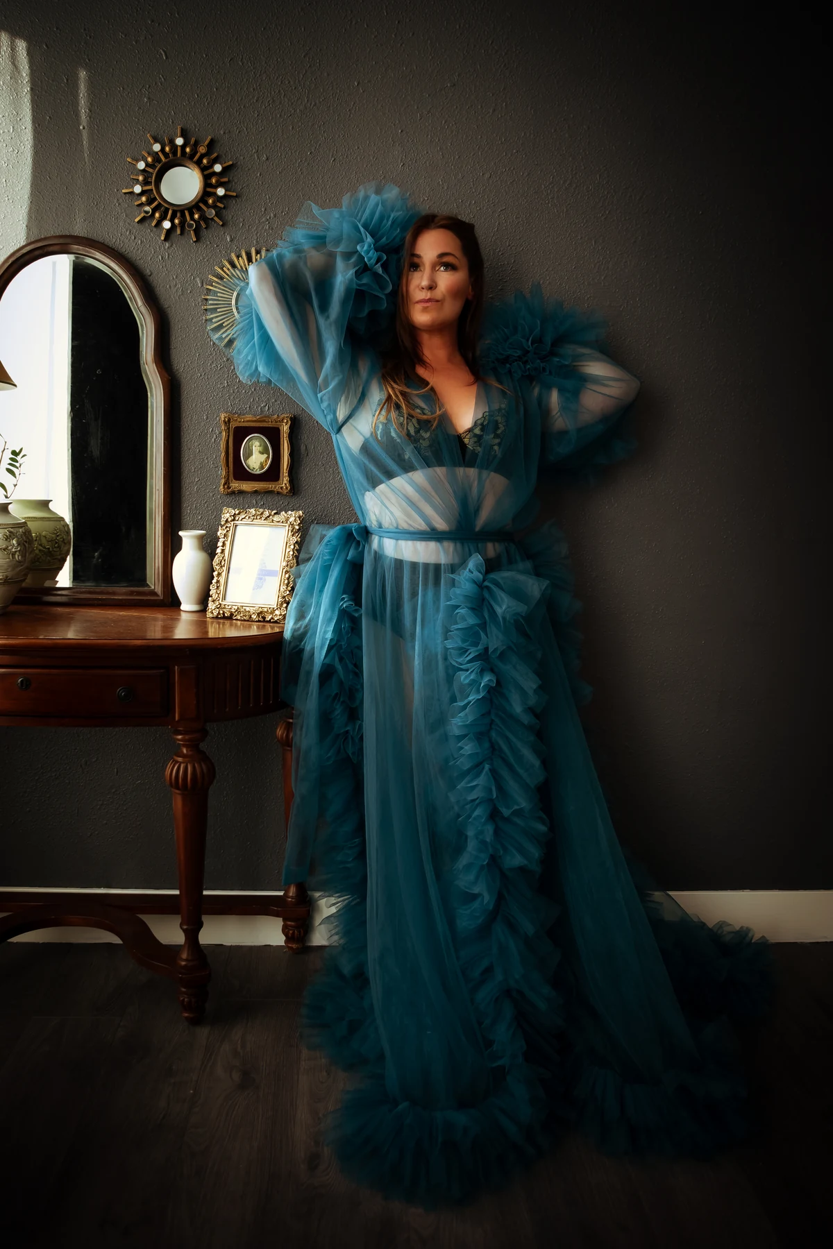 A woman standing confidently in a flowing blue robe in Mary’s studio.